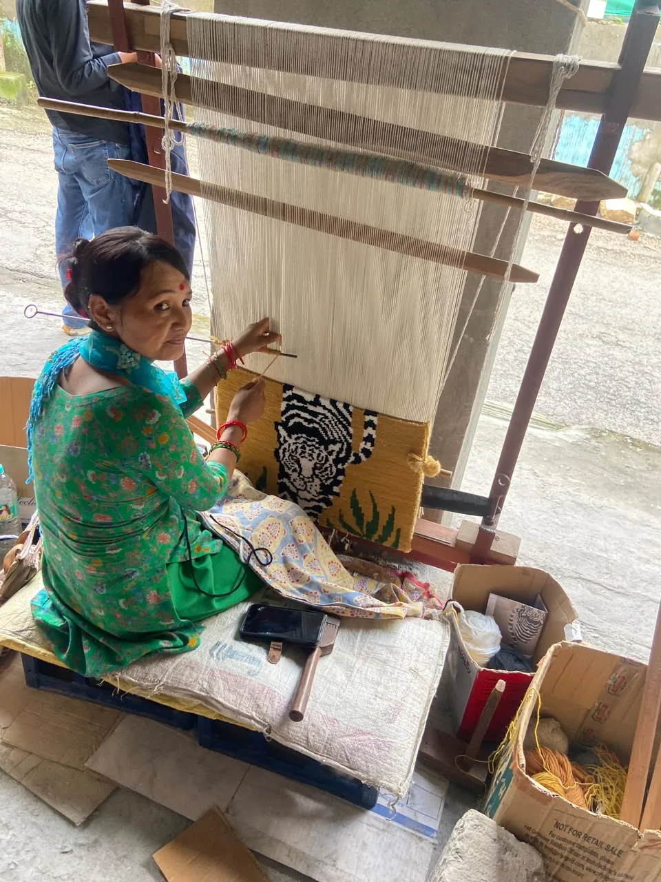 An artisan at the loom, a tiger design emerging from the warp